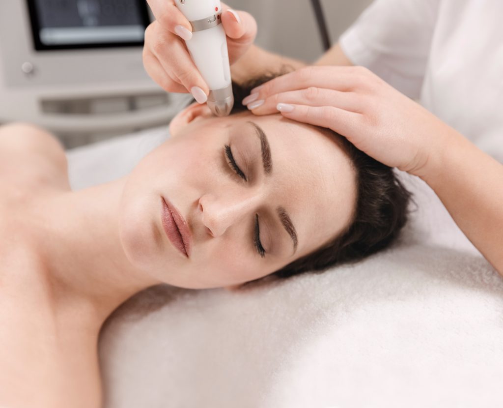 Dermadrop-TDA-Behandlung: das Handstück wird über die Wange einer liegenden Kundin geführt